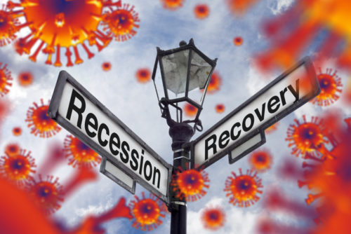 Two street signs showing the words "Recession" and "Recovery" on either side. This illustrates the concept of a global financial meltdown as the markets collapse under the pressure from the global pandemic caused by the virus Covid-19 (Coronavirus) and the recovery of markets.